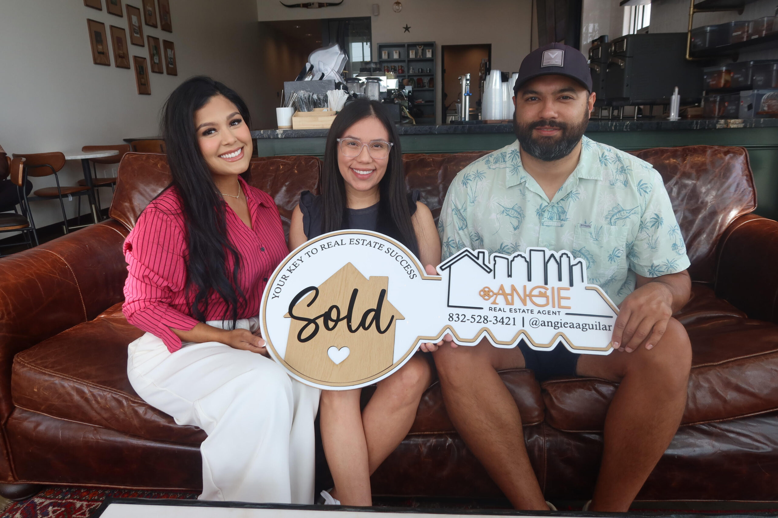 Clients holding a Sold key on a leather couch
