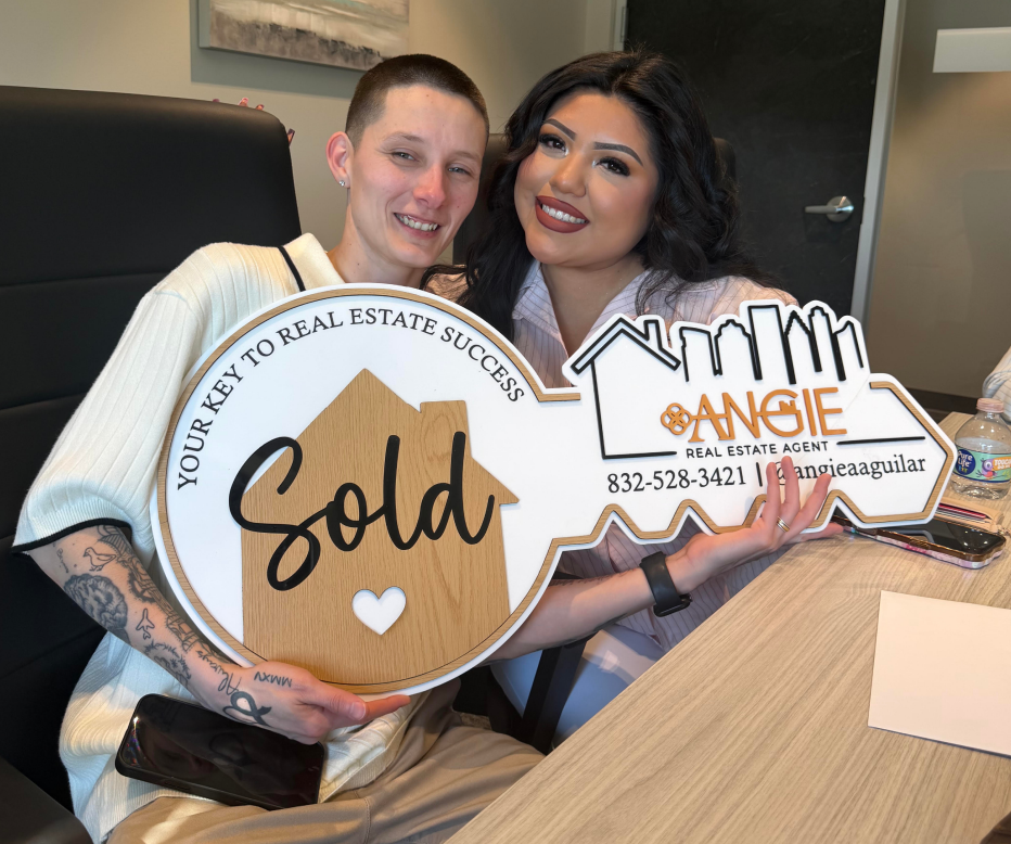 Two clients holding a Sold key at a closing table