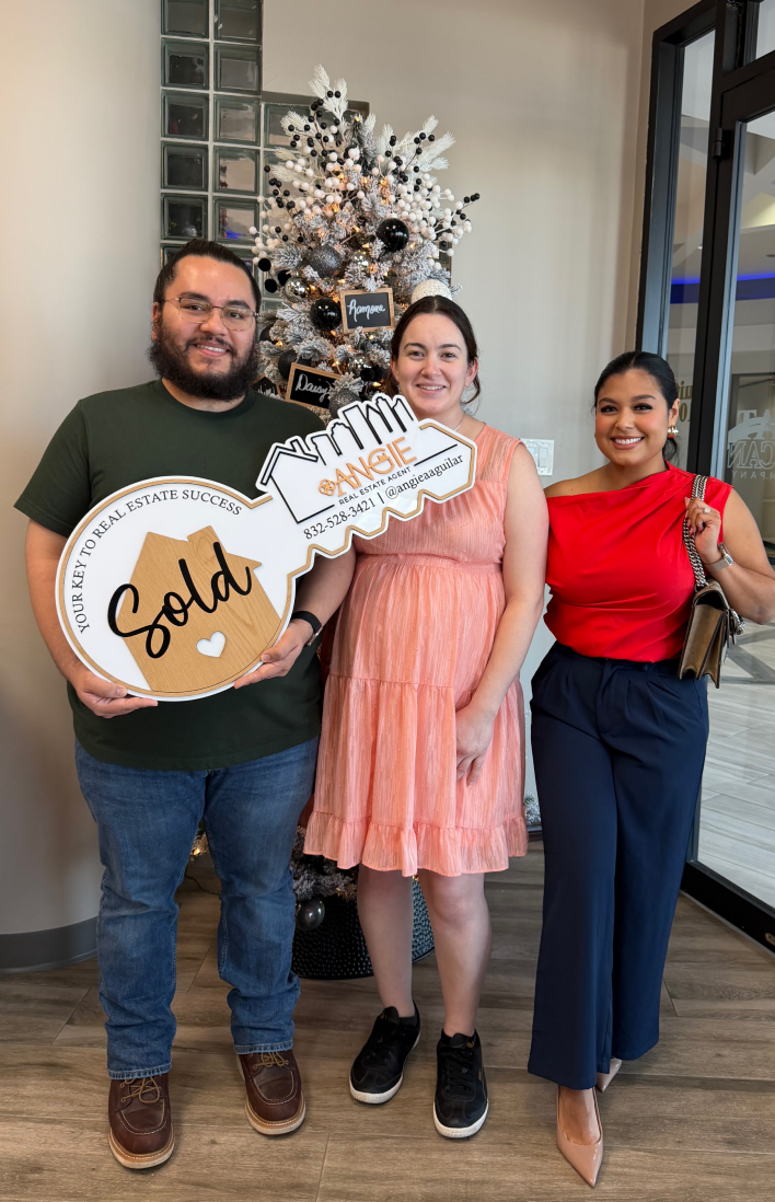 Clients holding a Sold key in front of a Christmas tree